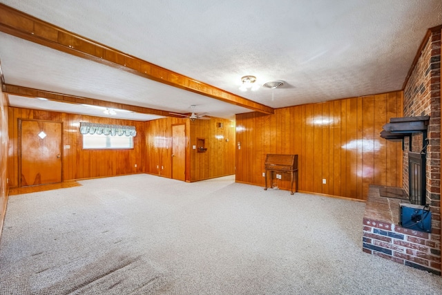 basement with carpet, a brick fireplace, a textured ceiling, and wooden walls