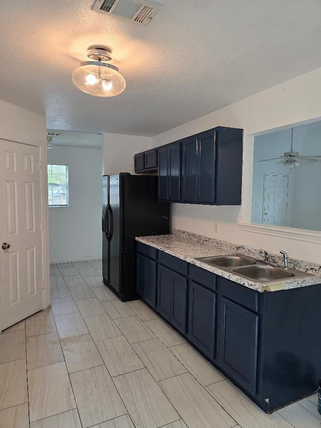 kitchen featuring sink, black fridge with ice dispenser, blue cabinets, a textured ceiling, and ceiling fan