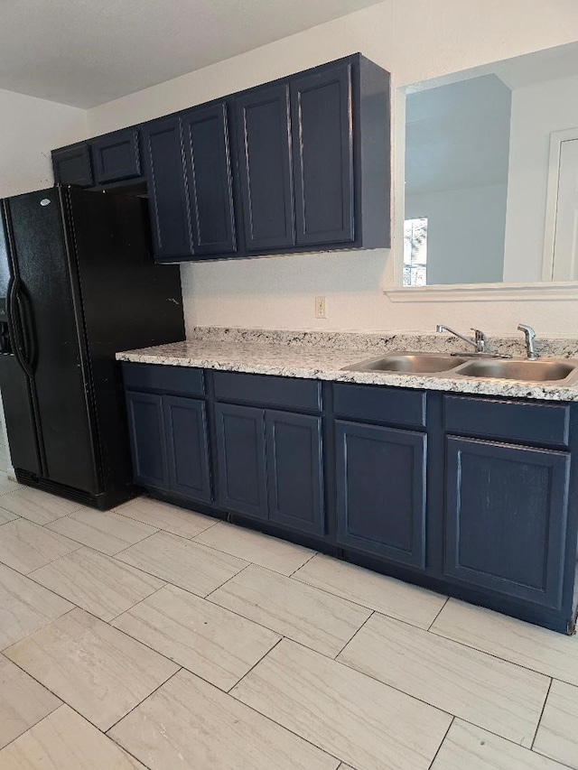 kitchen with sink, blue cabinetry, and black refrigerator with ice dispenser