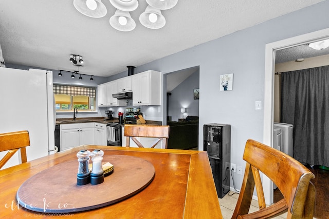 dining room with sink, a textured ceiling, rail lighting, and light tile patterned floors