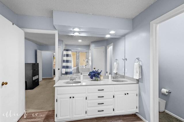 bathroom with toilet, wood-type flooring, vanity, a textured ceiling, and walk in shower