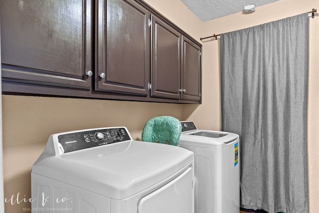 washroom with washer and dryer, a textured ceiling, and cabinets