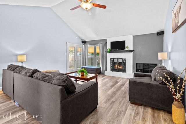 living room with light hardwood / wood-style flooring, high vaulted ceiling, a fireplace, and ceiling fan