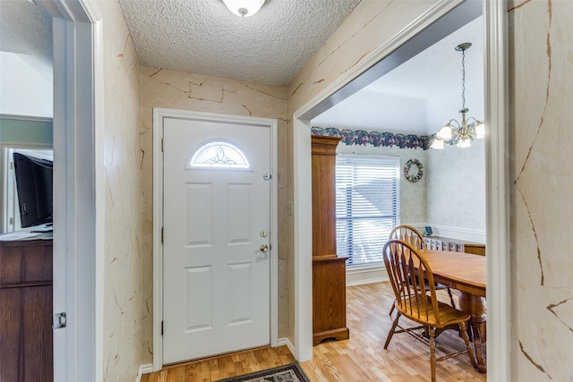 dining space featuring an inviting chandelier, lofted ceiling, a textured ceiling, and light wood-type flooring