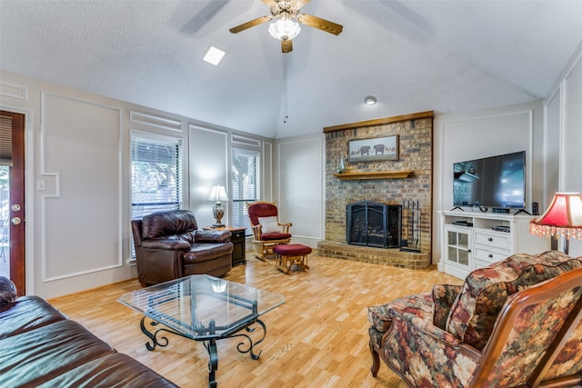 living room featuring a brick fireplace, hardwood / wood-style flooring, lofted ceiling, and ceiling fan