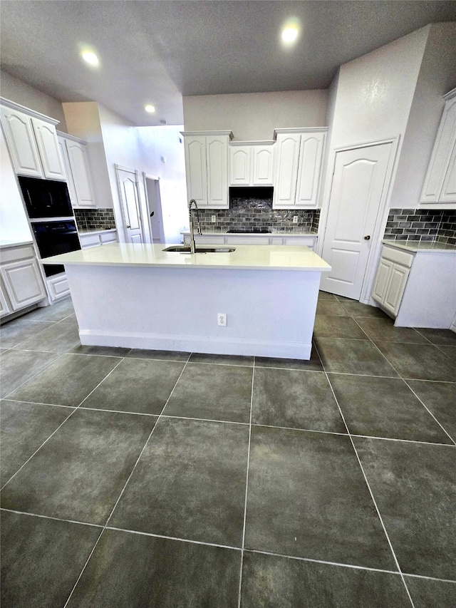 kitchen featuring sink, white cabinetry, and an island with sink