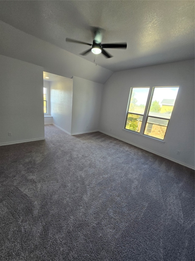 carpeted empty room with vaulted ceiling, a textured ceiling, and ceiling fan