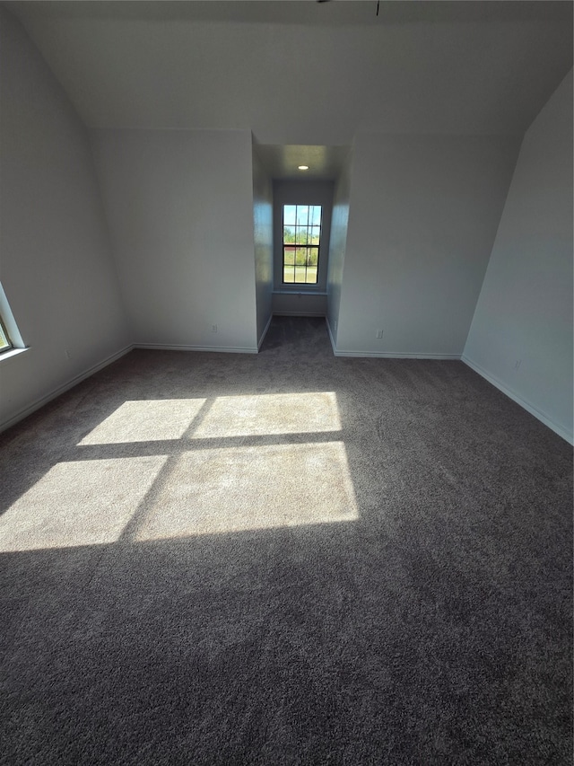 carpeted empty room with lofted ceiling