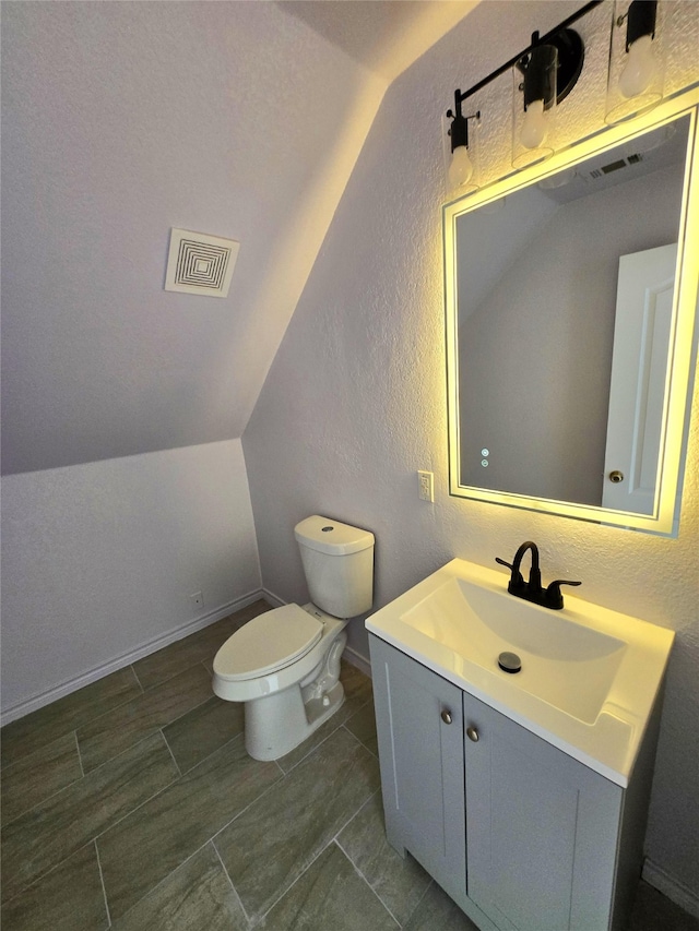 bathroom featuring vanity, lofted ceiling, and toilet