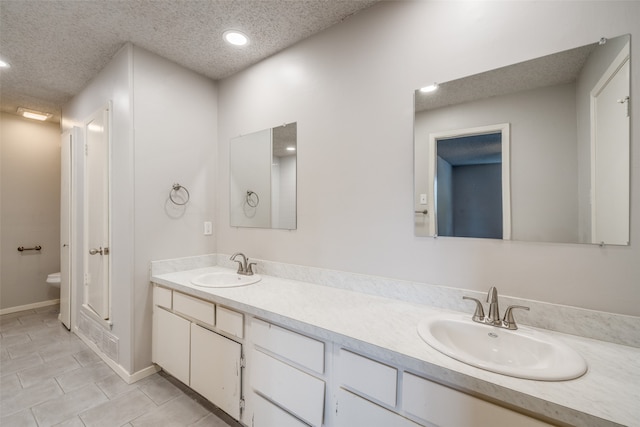 bathroom featuring vanity, toilet, a textured ceiling, and tile patterned flooring