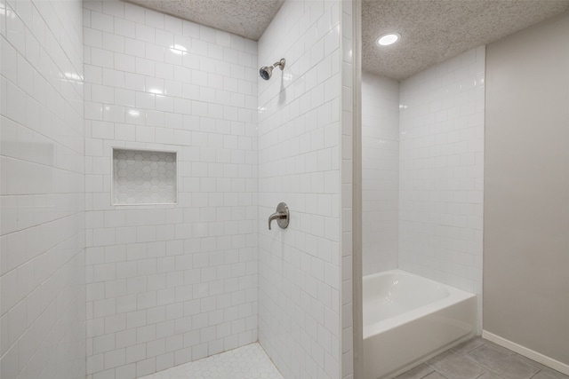 bathroom featuring tiled shower / bath, a textured ceiling, and tile patterned flooring