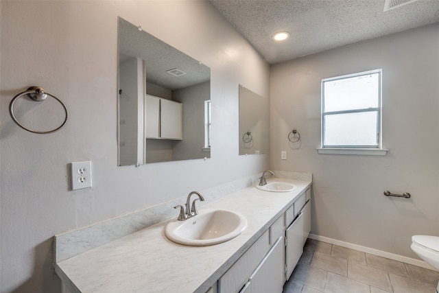 bathroom with toilet, a textured ceiling, vanity, and tile patterned flooring