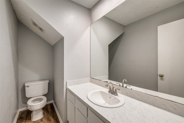 bathroom featuring vanity, a textured ceiling, hardwood / wood-style flooring, and toilet