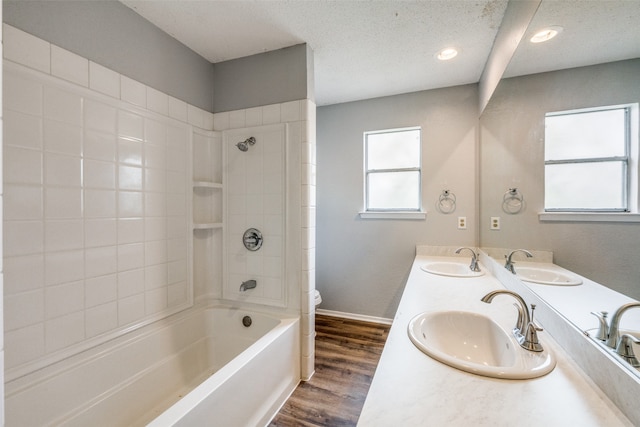 full bathroom featuring vanity, tiled shower / bath combo, wood-type flooring, and toilet