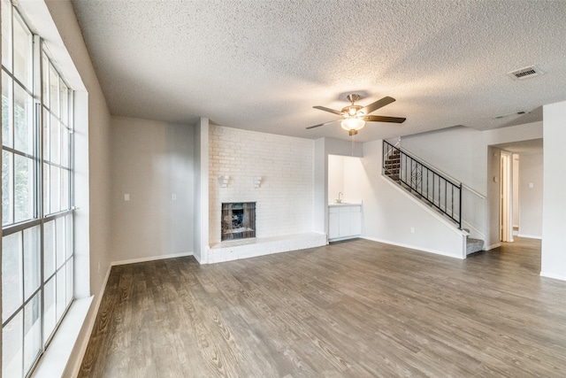 unfurnished living room featuring a textured ceiling, a fireplace, dark hardwood / wood-style floors, and ceiling fan