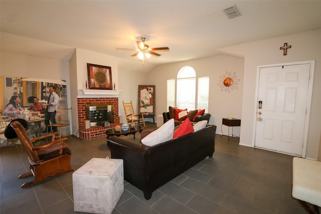 living room with dark tile patterned floors, ceiling fan, vaulted ceiling, and a fireplace