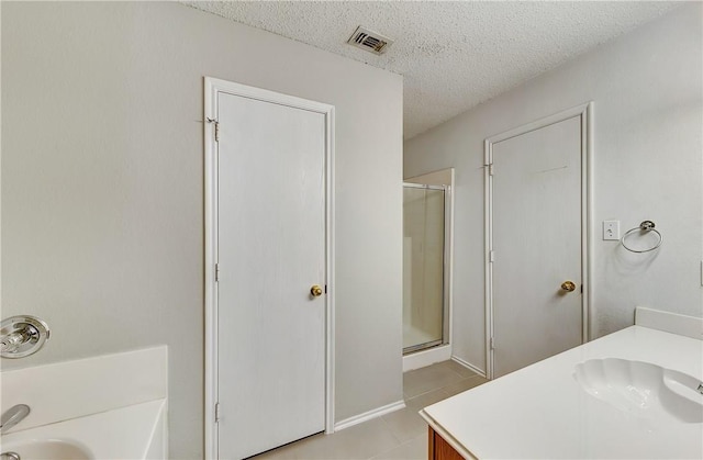 bathroom featuring walk in shower, tile patterned floors, vanity, and a textured ceiling