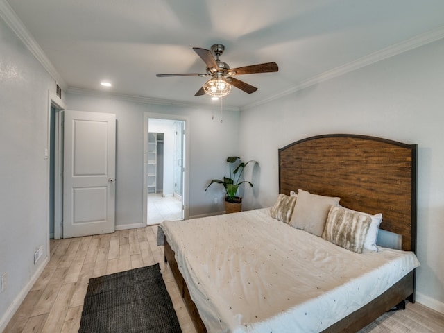 bedroom featuring ornamental molding, ceiling fan, a spacious closet, light hardwood / wood-style floors, and a closet