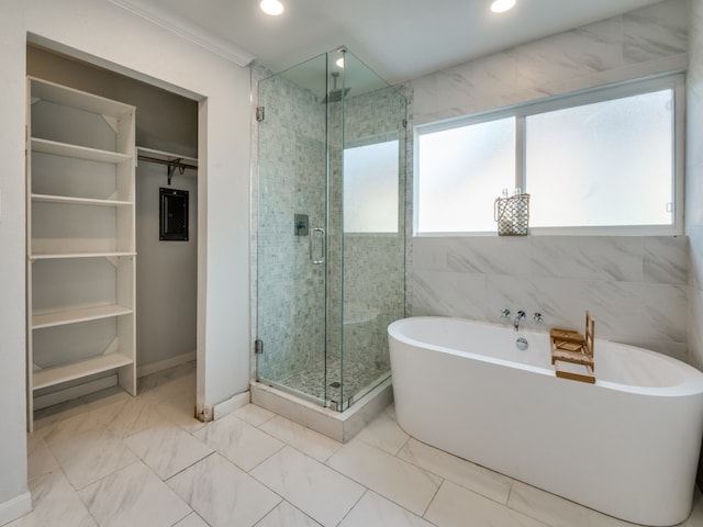 bathroom with plenty of natural light, electric panel, tile walls, and independent shower and bath