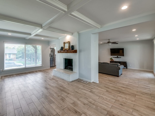 unfurnished living room featuring a fireplace, light wood-type flooring, ceiling fan, and beamed ceiling