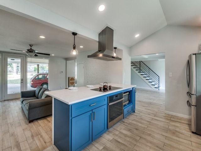 kitchen with wall chimney exhaust hood, stainless steel appliances, light hardwood / wood-style flooring, blue cabinets, and pendant lighting