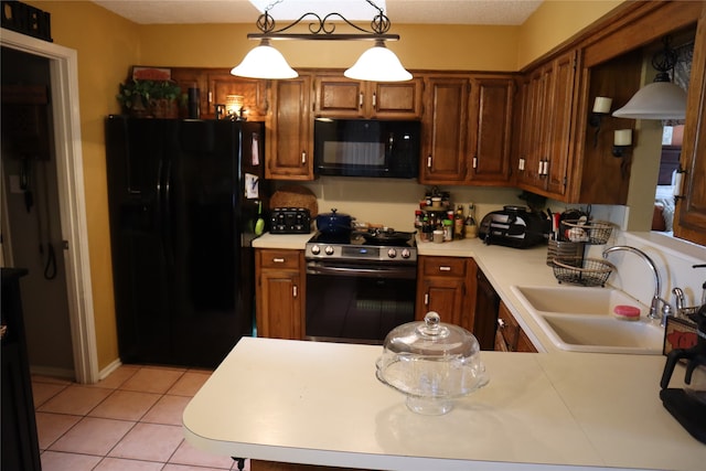 kitchen featuring sink, hanging light fixtures, kitchen peninsula, light tile patterned floors, and black appliances