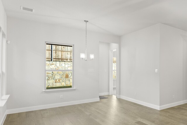 unfurnished room with light hardwood / wood-style flooring and an inviting chandelier