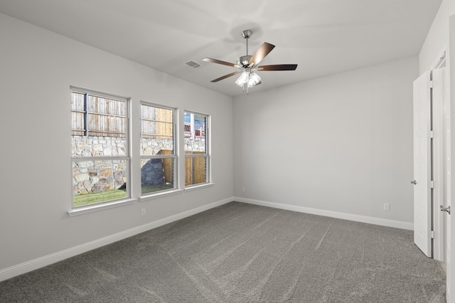 unfurnished room with dark colored carpet and ceiling fan