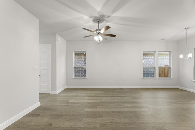 empty room featuring hardwood / wood-style flooring and ceiling fan with notable chandelier