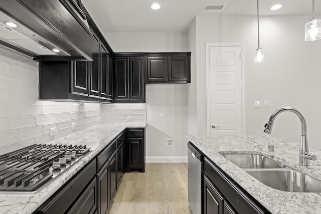 kitchen with pendant lighting, appliances with stainless steel finishes, sink, and light stone countertops