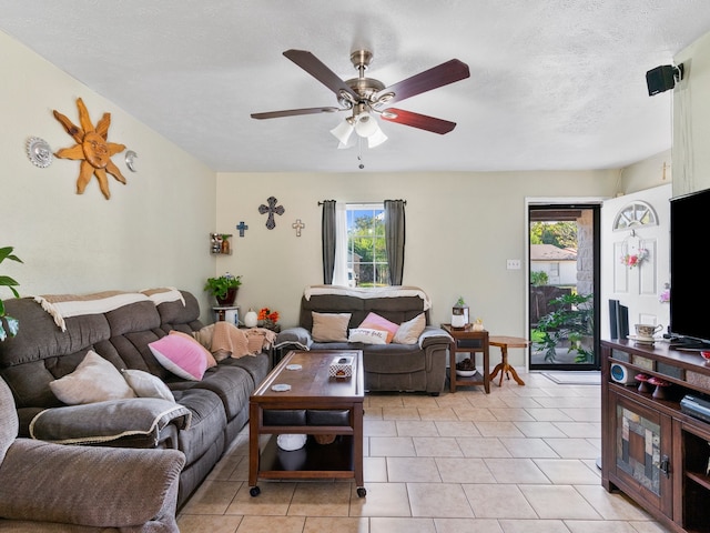 living room with ceiling fan, a healthy amount of sunlight, a textured ceiling, and light tile patterned floors