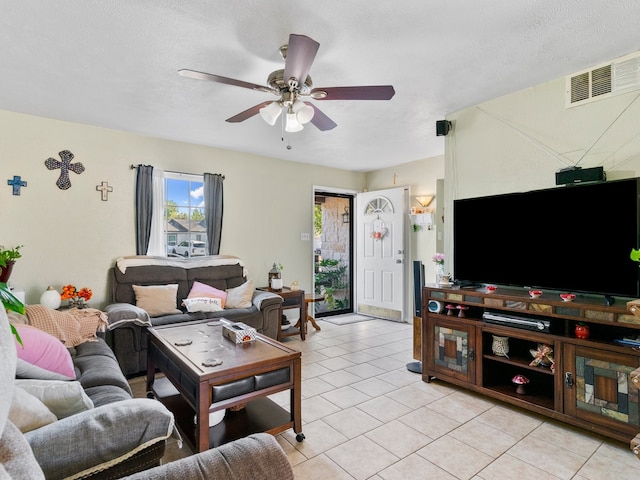 living room featuring a textured ceiling, ceiling fan, and light tile patterned floors