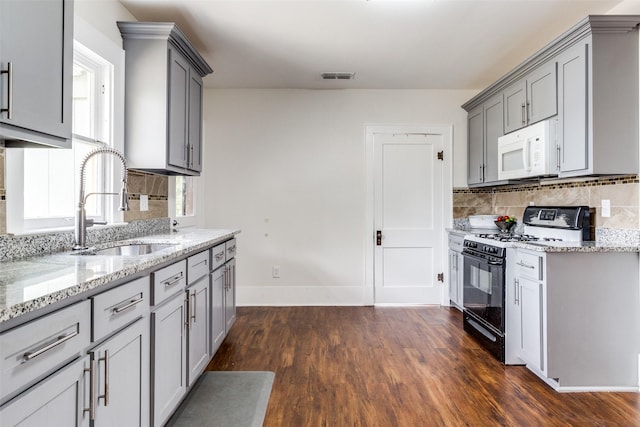 726 S Clinton Ave, Dallas, TX 75208 - kitchen featuring black gas range oven, white microwave, a sink, gray cabinets, and light stone counters