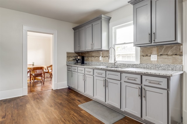 kitchen with gray cabinetry, sink, dark hardwood / wood-style floors, decorative backsplash, and light stone countertops