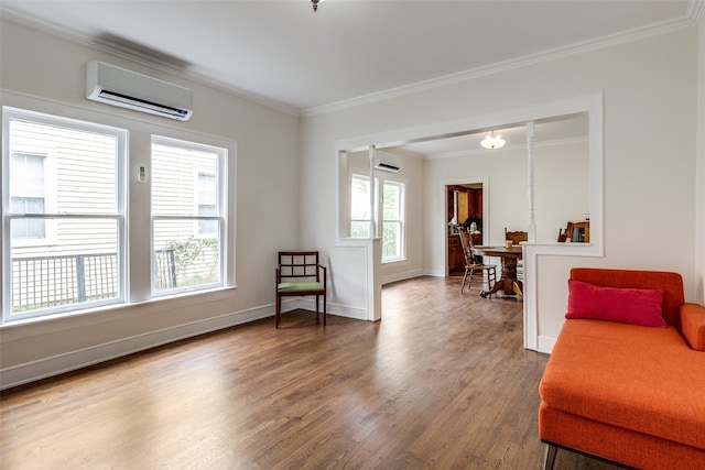 living area with a wall mounted air conditioner, wood-type flooring, and ornamental molding