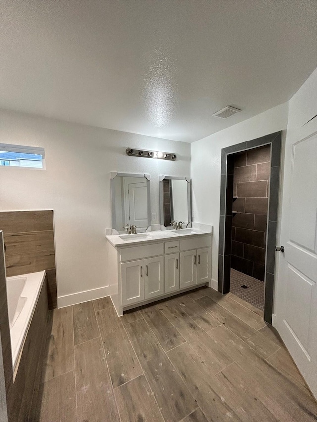 bathroom with a sink, a walk in shower, wood finished floors, and a bath