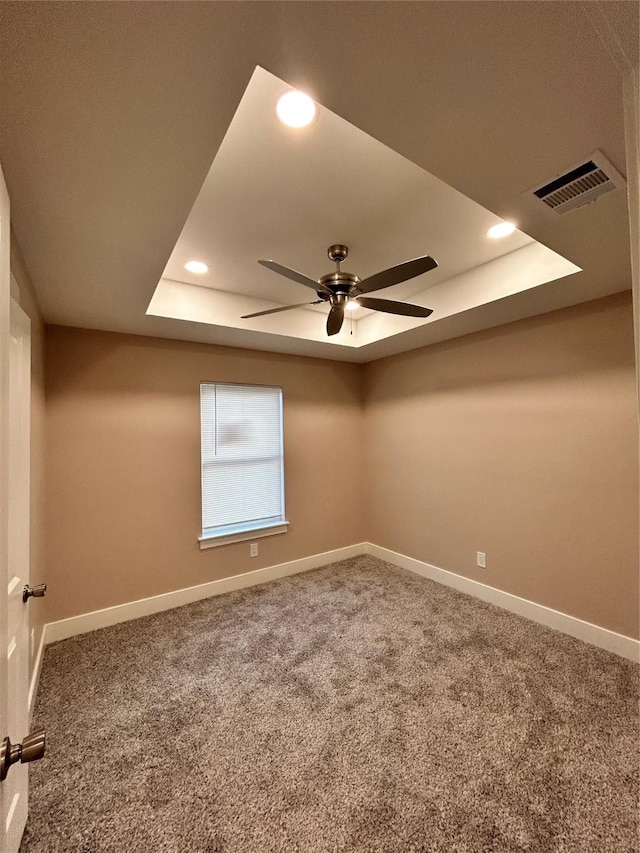 unfurnished room featuring carpet, visible vents, a tray ceiling, and baseboards