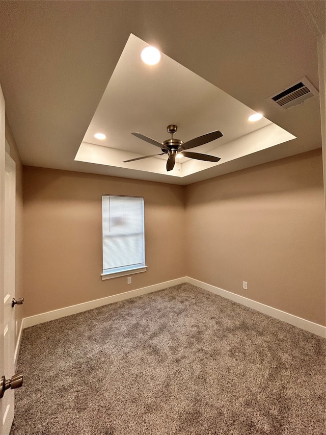 empty room featuring a tray ceiling, carpet, and ceiling fan