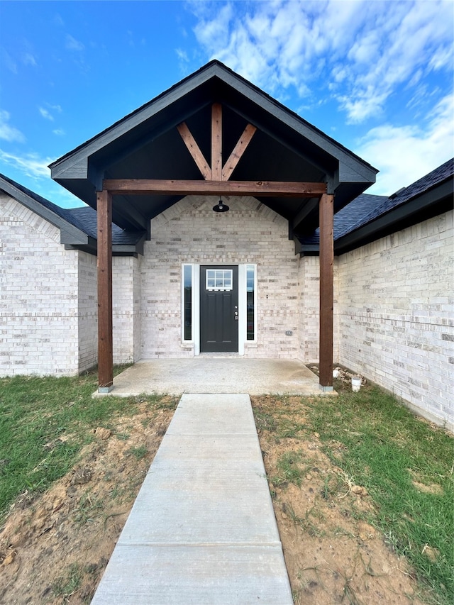 property entrance with a patio and a lawn