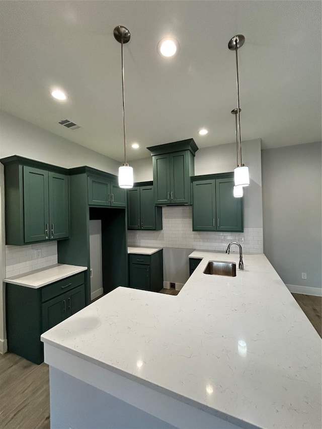 kitchen with a peninsula, a sink, light stone countertops, and pendant lighting