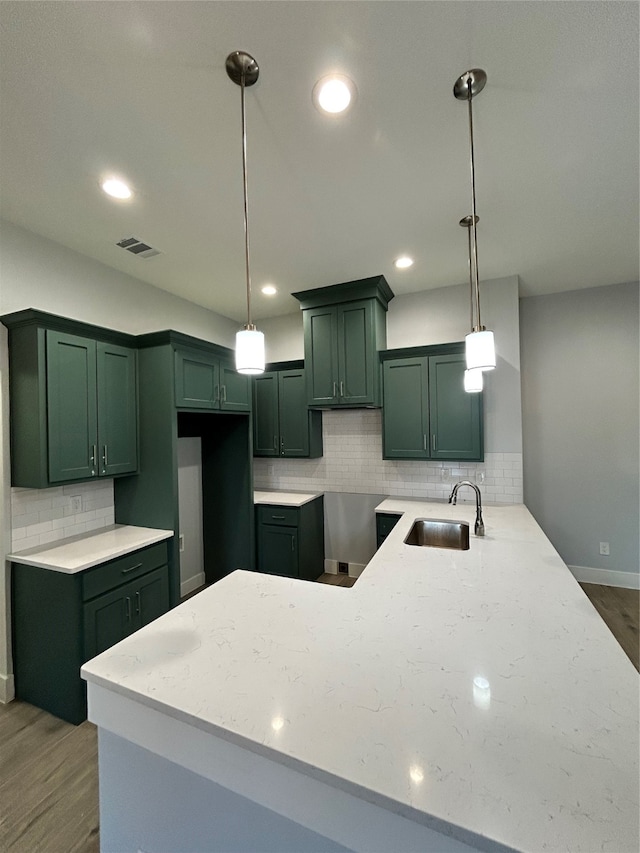 kitchen with kitchen peninsula, dark hardwood / wood-style floors, sink, and pendant lighting