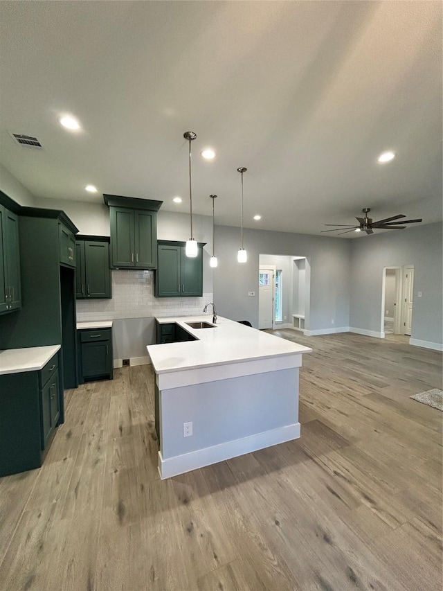 kitchen with light countertops, light wood finished floors, a sink, and decorative light fixtures