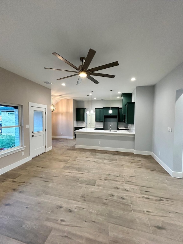 unfurnished living room with ceiling fan, recessed lighting, light wood-style flooring, and baseboards