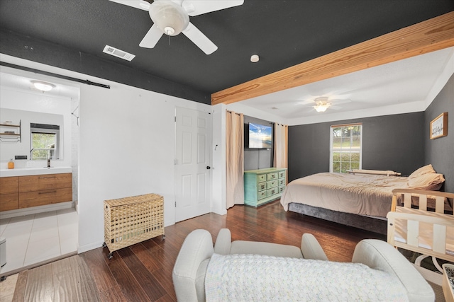 bedroom with dark wood-type flooring, ceiling fan, multiple windows, and a barn door