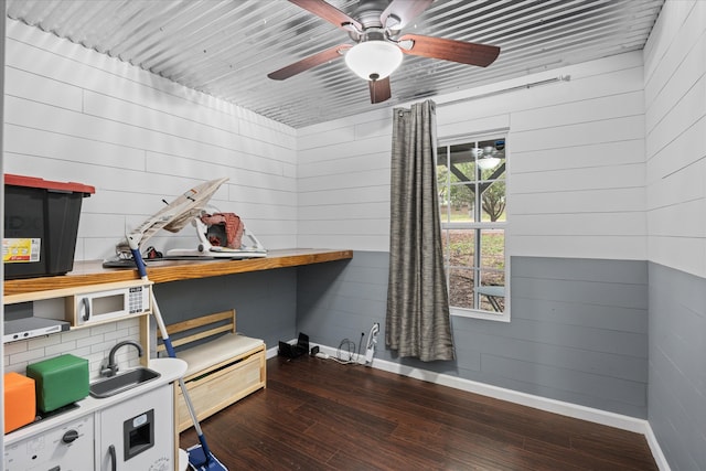 miscellaneous room featuring ceiling fan, wood walls, and dark hardwood / wood-style flooring