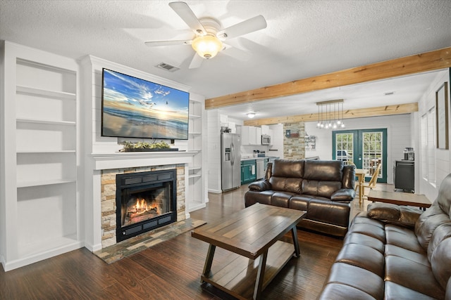 living room with ceiling fan, a textured ceiling, dark wood-type flooring, a stone fireplace, and french doors