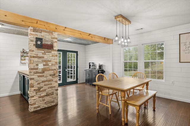 dining space with wood walls, a textured ceiling, and dark wood-type flooring