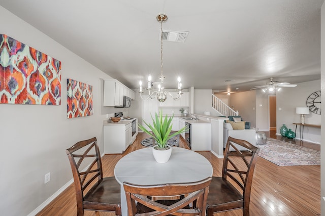 dining room featuring sink, ceiling fan with notable chandelier, and light hardwood / wood-style flooring