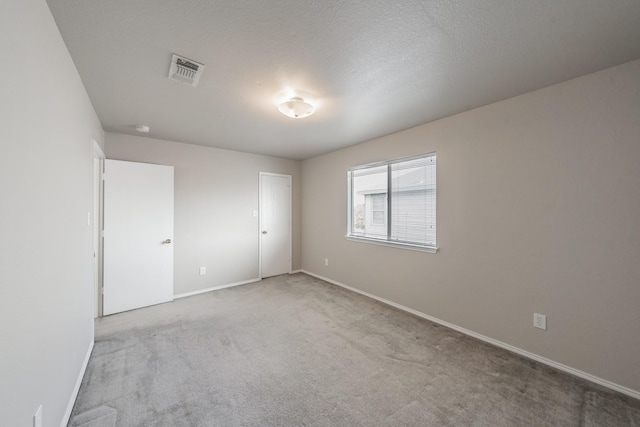 unfurnished room with light colored carpet and a textured ceiling