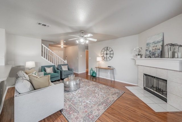 living room featuring ceiling fan, a fireplace, and light hardwood / wood-style floors